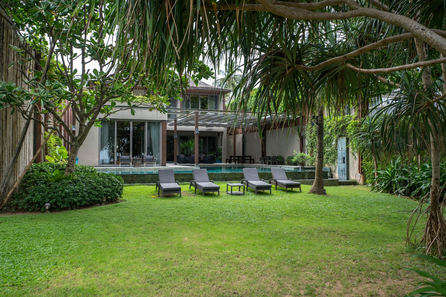 Moderne villa met zwembad en ligstoelen op het gazon.