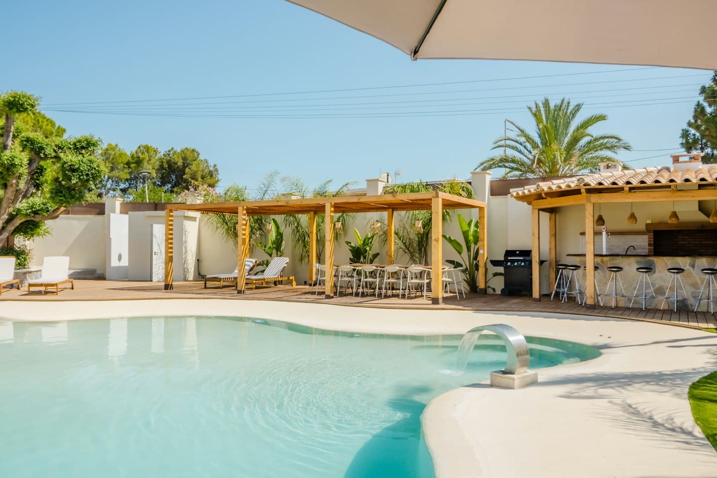 Zwembad in de achtertuin met een pergola en een eethoek buiten.